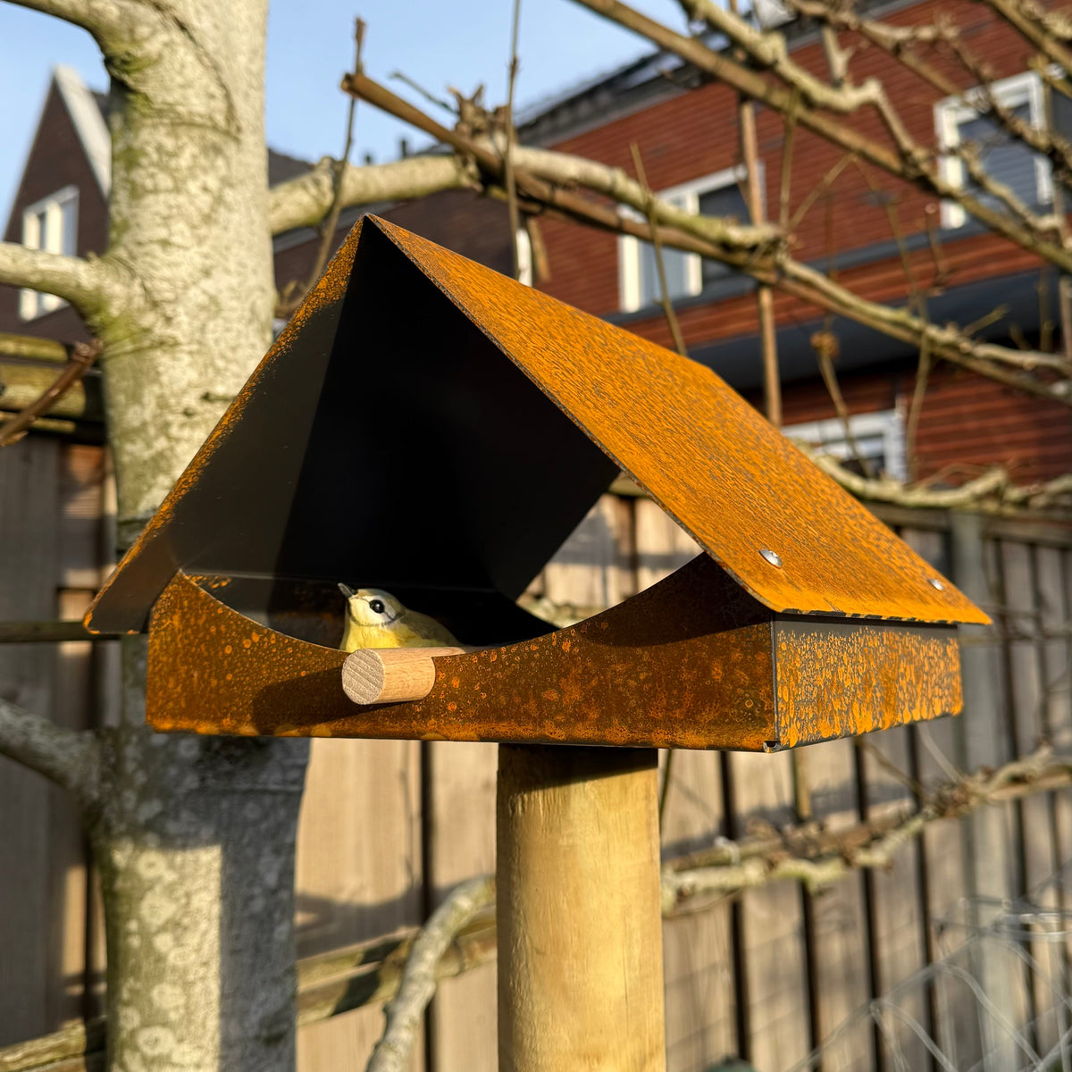 Design vogelvoederhuis KRAM van cortenstaal met zadeldak, geschikt voor montage op houten paal (niet inbegrepen).